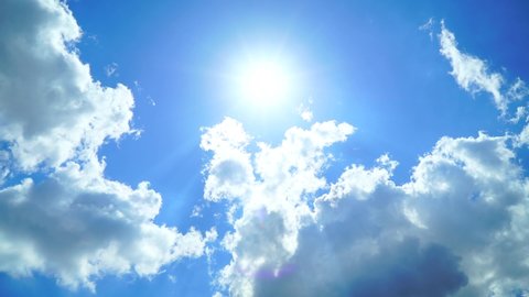 Low Angle view TimeLapse of direct bright noon sun on blue sky with clouds,sun shining on  summer hozizon in vibrant sunlight,sunbeam & sun ray flares with white cumulus clouds at midday sunshine day 库存视频