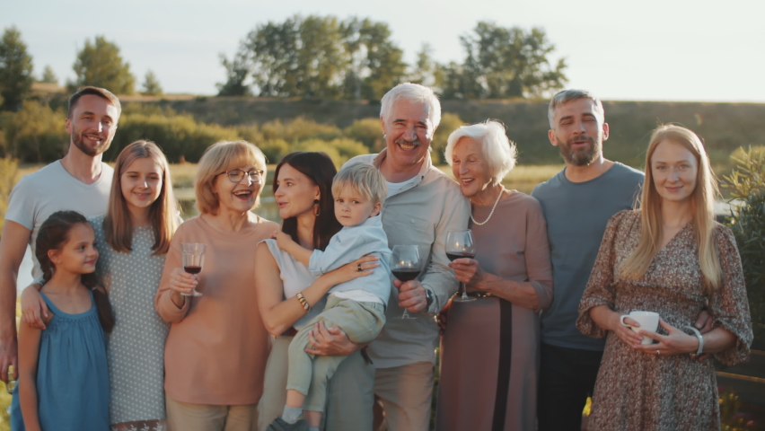 Large Caucasian family standing together outdoors, posing for camera and smiling while gathering together on summer weekend | Shutterstock HD Video #1061537008