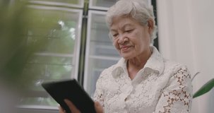 Slow motion Asian Senior Woman Waving Hand To Tablet Computer. Old Woman Using Tablet Device For Video Call.