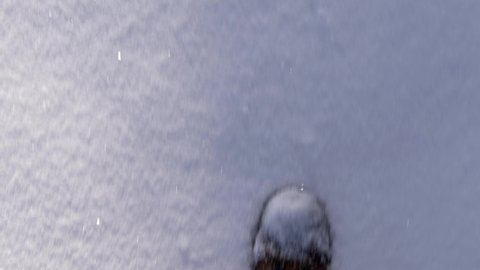A man walks through the snow in winter shoes and brown pants. Feet of a man walking on fresh snow in the first person. Concept of travel, winter holidays and walks in the Park. 