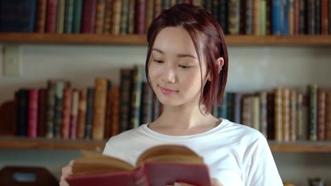 Young asian woman reading books in the library.