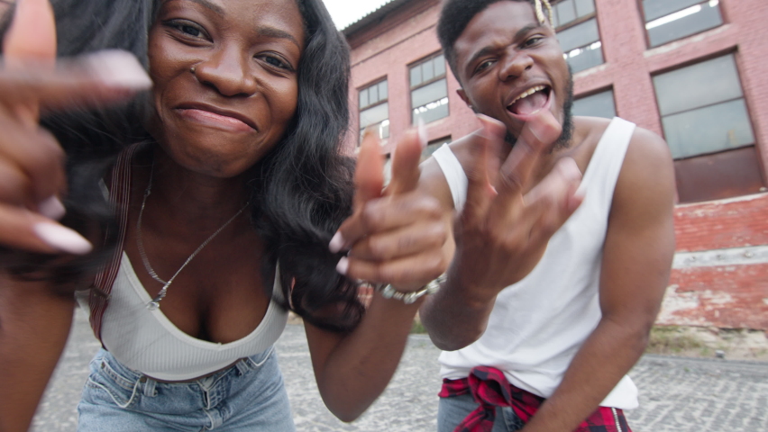 Street Dancing. Young Couple Dancing On The Street. Black Guy And Girl Move Rhythmically. They Make Movements And Smile. Behind Them Are Old Houses. Cute Young People In Jeans. Stylish Guy With Beard
