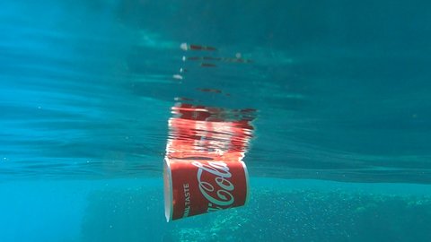 RED SEA, EGYPT - OCTOBER, 2020: Coca-Cola red cup slowly floats underwater reflecting off the surface of the blue water. Coca-Cola ranked No 1 for most littered products. Plastic pollution of Ocean