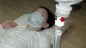 4K intravenous saline drip with child patient's face out of focus. UHD stock video