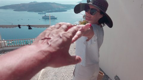Beautivul woman with hat enjoy summer vacation walking on streets of Santorini