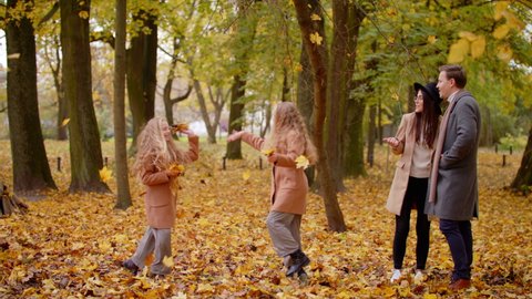 View Of Family Mother Father And Twins Sisters Having Fun With Autumnal Leaves Laughing And Throw Leaves Friendly Family Kid Concept Autumn Countryside Slow Motion