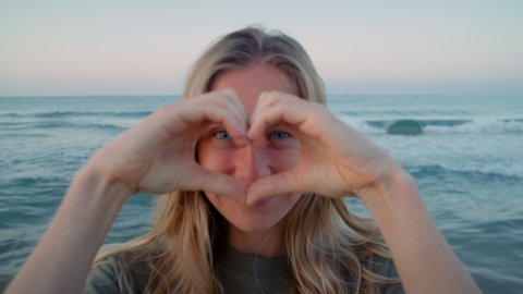 Woman make heart sign with her fingers. Concept love for nature and consciousness about ecological projects. Romantic getaway vacation vibes, happy real feelings and emotions. Authentic smile