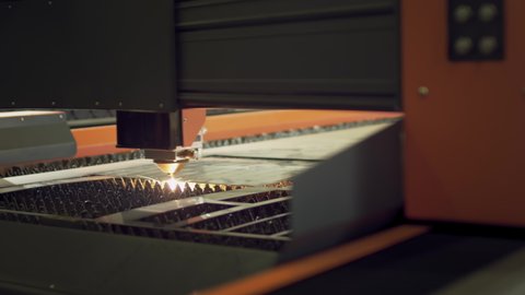 Laser cutting of metal. An industrial machine with a powerful luminous beam cuts a thick sheet of metal. Metalworking at the plant. CNC laser machine for cutting metal plate on industrial manufacture