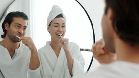 Slow motion of young cheerful man and woman brushing teeth having fun and laughing looking at mirror in bathroom. Relationship and health concept. - Powered by Shutterstock - Get 15% off with code: PIKWIZARD15