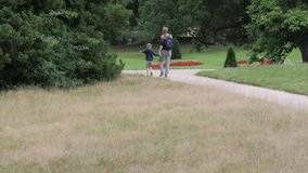 Medium shot father with son by the hand walking at the park. Slow motion 4K