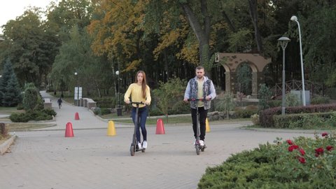 Happy couple riding on gyrocooter outdoors at the autumn city park