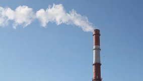 Steam and smoke coming out of a factory chimney against a cloudy sky. Air pollution concept, emissions, station, climate change, global warming, oil refinery, industry