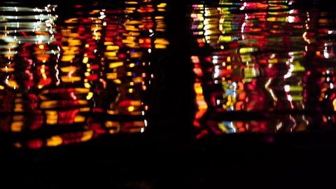 The night river water waves reflects the bright street colorful light, close up. Hoi An, Vietnam