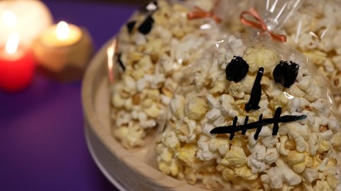 Goodies for Halloween party, Popcorn in the form of spooky skull, Halloween food with candles in the background