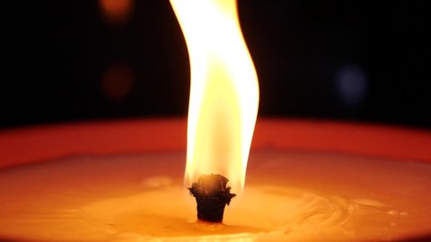 Candle flame close up in super slow motion. Candle burning at grave.  Candle burning at cemetery. Burning candle on a dark background. 