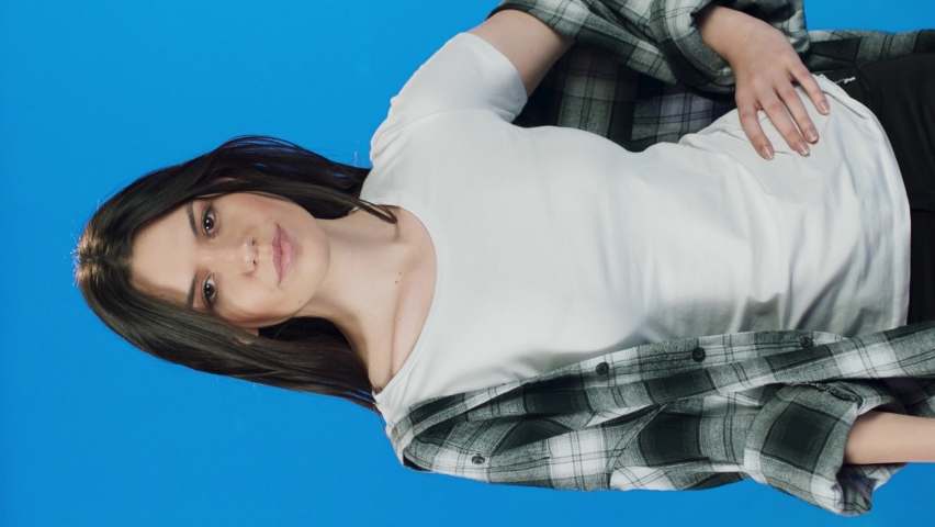 Fashion pretty pretty woman holding red umbrella over blue background wearing t-shirt and shirt.Woman with umbrella on blue background.Video for the vertical story.
