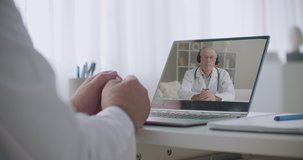 head physician and medical specialist are communicating online by laptop with internet, closeup of hands