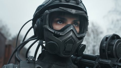 Portrait female future soldier in fiction helmet after nuclear war. Lonely star trooper cyborg girl in futuristic combat suit with assault gun. Cyberpunk military post apocalypse concept.