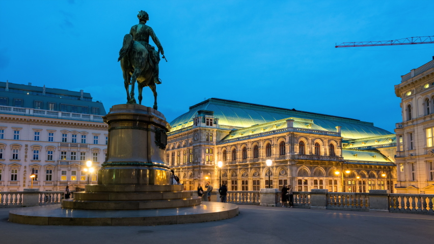 Beautiful view of Wiener Staatsoper (Vienna State Opera) aerial day to night transition timelapse in Vienna, Austria. Illuminated historic buildings and traffic on streets