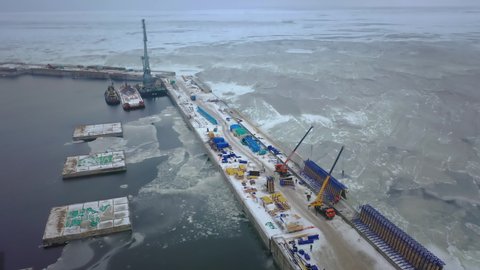 Construction of a berth for the shipment of liquefied natural gas. We see a mooring structure under construction. Around it is water covered with ice.