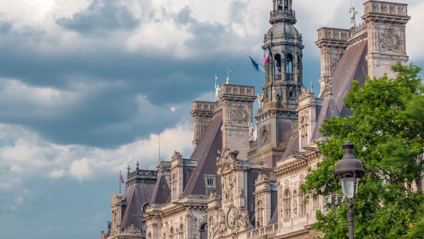 Architecture of The Hotel de Ville City Hall with french flag on tower timelapse, the building housing the local administration of the city of Paris. Cloudy sky at summer day. Close up view