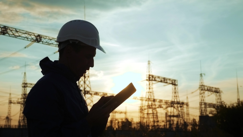 electrical worker silhouette engineer a working with digital tablet, near tower with electricity.  Royalty-Free Stock Footage #1061588848