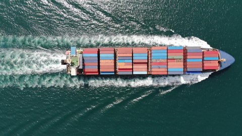 Aerial top view of smart cargo ship carrying container and running very fast for export cargo from container yard port to custom ,Contrail line in the ocean by large ship very fast. 