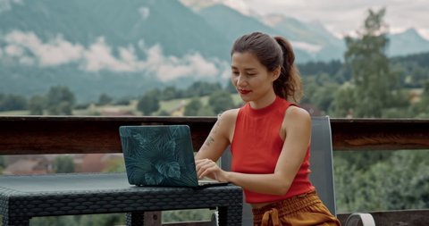 Pretty lady enjoying fresh air and lonelines on tarrace using computer in outdoor office. Social distance working. Asian woman sitting alone in her garden and working on laptop. Isolation quarantine