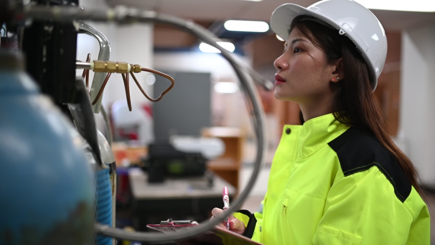 Asian engineer working at Operating hall,Thailand people wear helmet  work,He worked with diligence and patience,she checked the valve regulator at the hydrogen tank. | Shutterstock HD Video #1061597926
