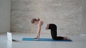 Slender woman stretching and multifunctional workout during online video conference with instructor. Sportswoman fitness training at home in quarantine