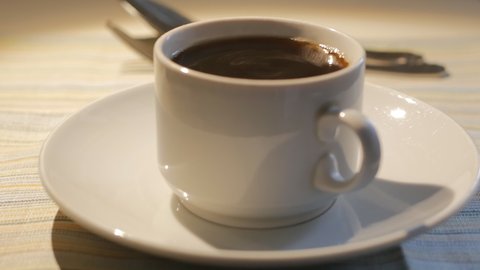 the white cup of poured coffee is shaking from the tremors of the earthquake. Vibration of liquids and utensils is a sign of a potential natural disaster. 4k.
