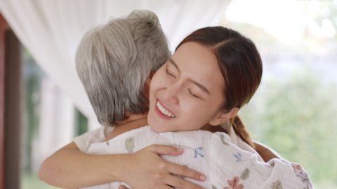 Happy Asian family young daughter embracing or hugging old mother at home, miss, love, warm and happy family