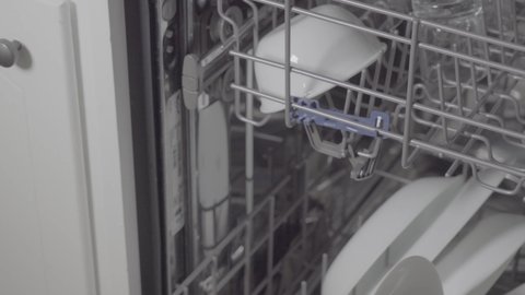Top rack of dishwasher loaded with drinking glasses being pulled out.