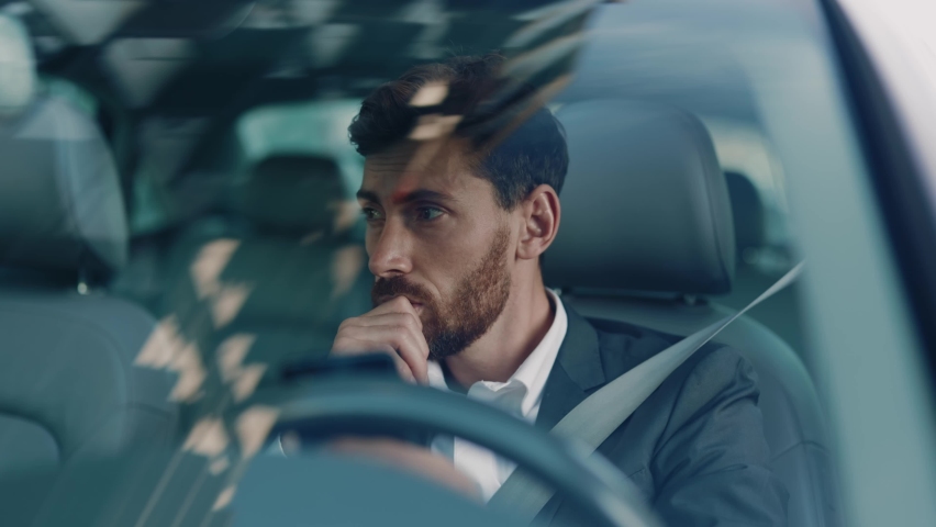 Disappointed young adult businessman waiting in traffic jam getting bored using mobile phone commuting late for work. Road adventures. City transportation. Emotions. | Shutterstock HD Video #1061608729