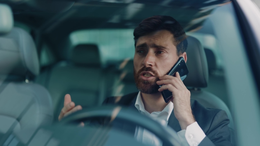 Stressful adult businessman waiting in traffic jam calling transport services receiving no answer getting angry. Angry emotions. Frustration, tiredness. Commuting. | Shutterstock HD Video #1061608735