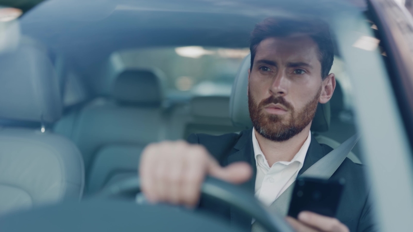 Confident focused caucasian adult businessman using smartphone application dialing colleague communicating online and driving car. Commuting. Business people lifestyle. | Shutterstock HD Video #1061608747