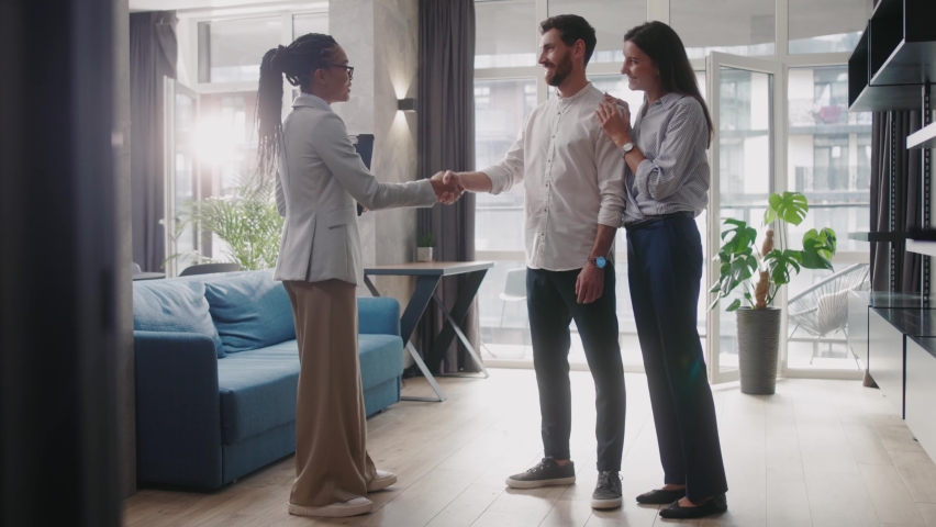 Female housing agent shaking hands with caucasian man reaching agreement of buying new house. Stylish apartment. Woman realtor. Multi-ethnic people. | Shutterstock HD Video #1061608840