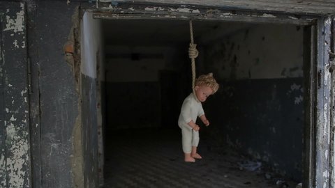 Hanged baby doll. A baby doll hangs in a noose in an abandoned building.

