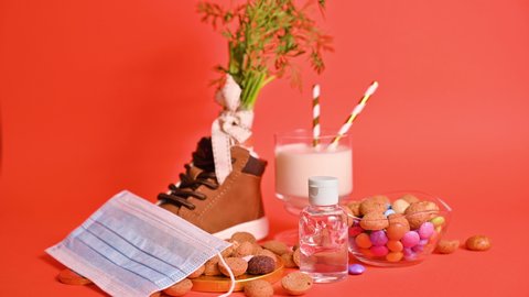 Dutch holiday Sinterklaas. hildrens shoe with carrots for Santa's horse, pepernoten and sweets . Gloved hands are rubbed with antiseptic, sanitizer and a protective mask.