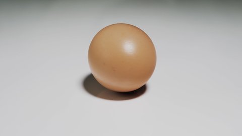 Chicken egg rotates on a white background. Close-up of an egg