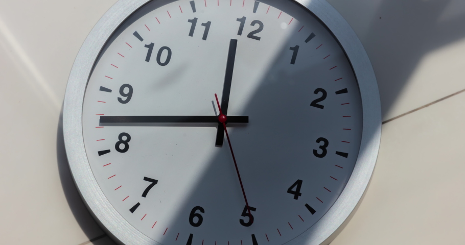 Wall clock show the running time. Time lapse on a modern wall clock.  Close up to a wall clock, with running time pointer. Sun and sky reflecting in the watch during the time passing by | Shutterstock HD Video #1061617441