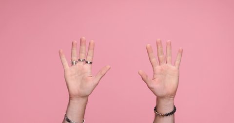 two hands counting up from one to five on each hand on pink background