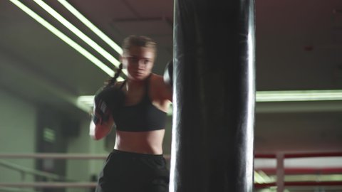 Boxing, woman fighter trains his punches, beats a punching bag, training day in the boxing gym, strength fit body, the girl strikes fast.
