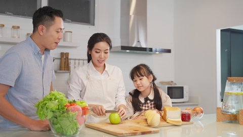 Family relationship, Asian happy family making food preparation in kitchen room at house. Father mother and children having fun spending time together. Dad and little girl looking at mom cooking food.