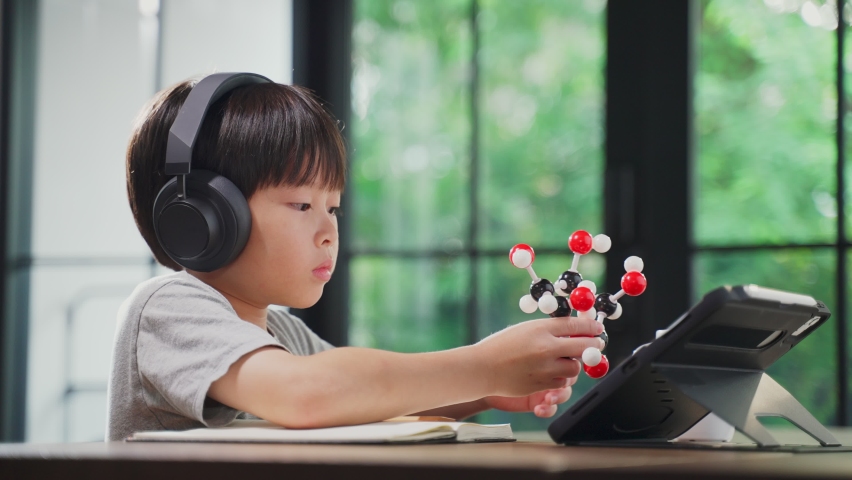 Asian little boy assembling molecular model by learning from home with school teacher teaching online. Homeschool kid practicing to think about logic and conference with teacher by remote application. Royalty-Free Stock Footage #1061631001