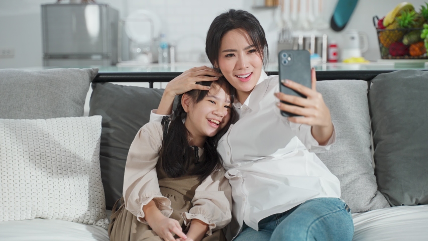 Asian family little kid girl and mother talking in video conference by smartphone together in living room at home with happiness and smile. Happy activity technology lifestyle mobile phone use concept Royalty-Free Stock Footage #1061631247