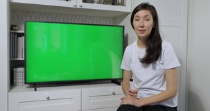 Young female teacher communicate with student by webcam video call. Concept of distance education. Blank green screen tv on background for visual aids
