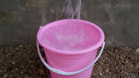 Slow motion footage of water overflow in a bucket causing wastage of water