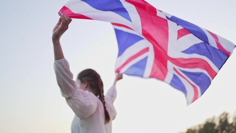 A British person carries the national flag in her hands. The symbol of Great Britain waving on the wind