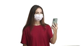 Coronavirus, social distancing and pandemic concept. Happy attractive woman in red t-shirt and medical mask communicate with friends via video call, waving hand to say hi and smiling at mobile phone